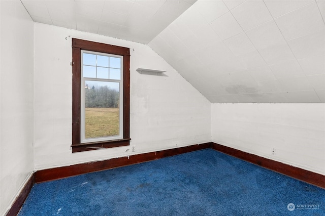 additional living space with dark colored carpet and lofted ceiling