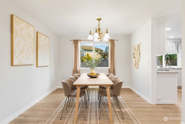 dining area with sink, a chandelier, and light hardwood / wood-style floors