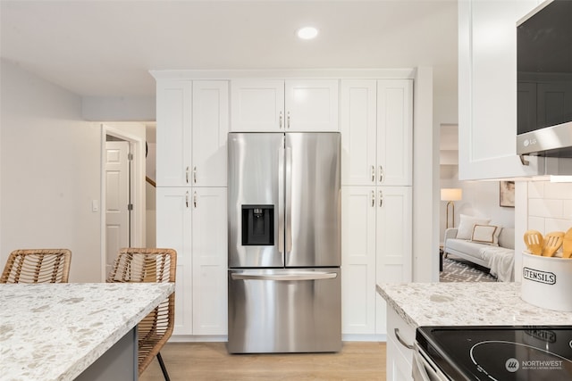 kitchen featuring stainless steel appliances, white cabinetry, and light stone counters