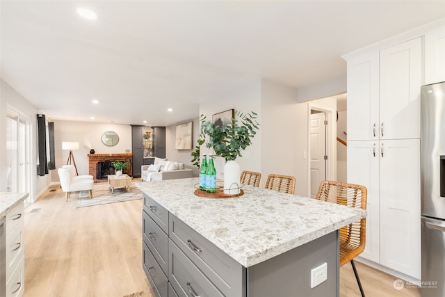 kitchen featuring a fireplace, white cabinets, a kitchen breakfast bar, and stainless steel fridge with ice dispenser