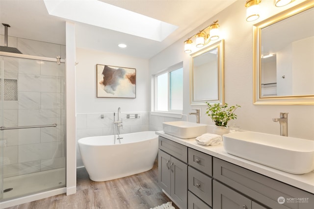 bathroom featuring vanity, a skylight, wood-type flooring, and shower with separate bathtub