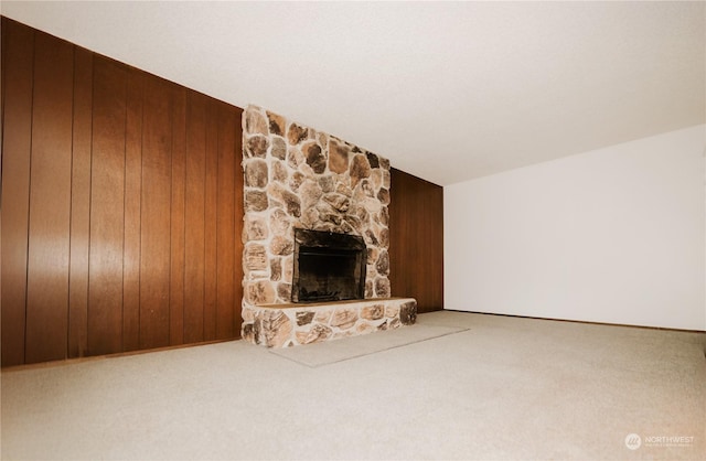 unfurnished living room with wooden walls, a fireplace, and carpet floors