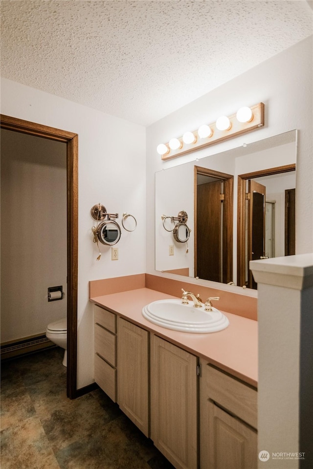 bathroom featuring a baseboard heating unit, vanity, a textured ceiling, and toilet