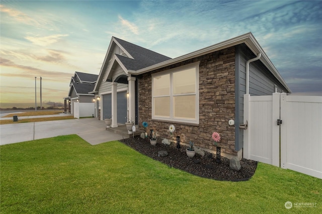 property exterior at dusk featuring a yard and a garage