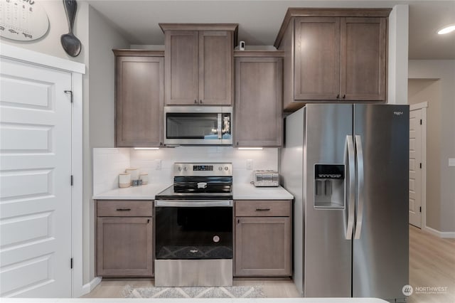 kitchen featuring appliances with stainless steel finishes, backsplash, and light hardwood / wood-style floors