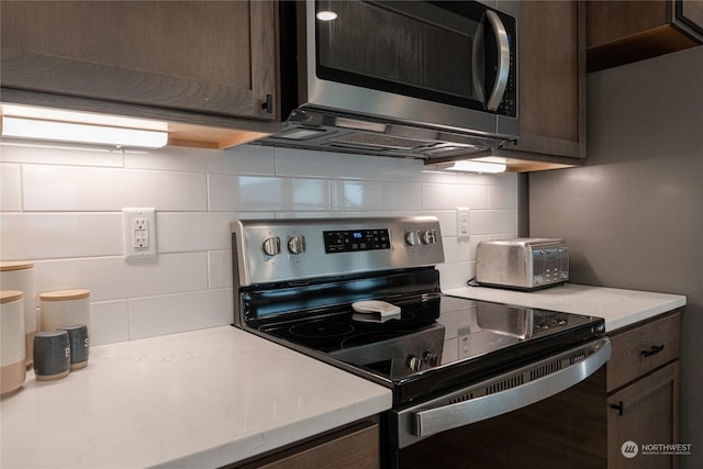 kitchen with tasteful backsplash, dark brown cabinetry, appliances with stainless steel finishes, and light stone counters