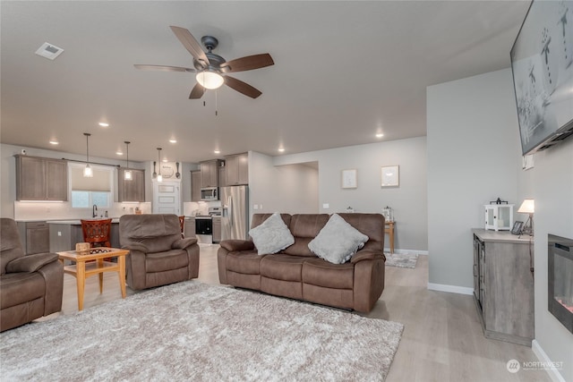 living room with ceiling fan and light hardwood / wood-style flooring