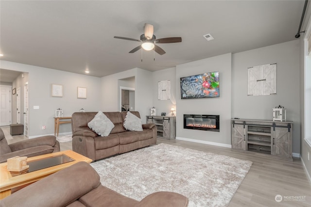 living room featuring ceiling fan and light hardwood / wood-style flooring