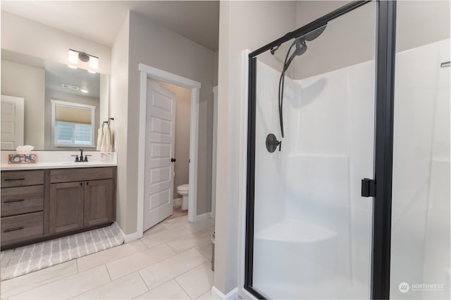 bathroom featuring tile patterned flooring, vanity, an enclosed shower, and toilet