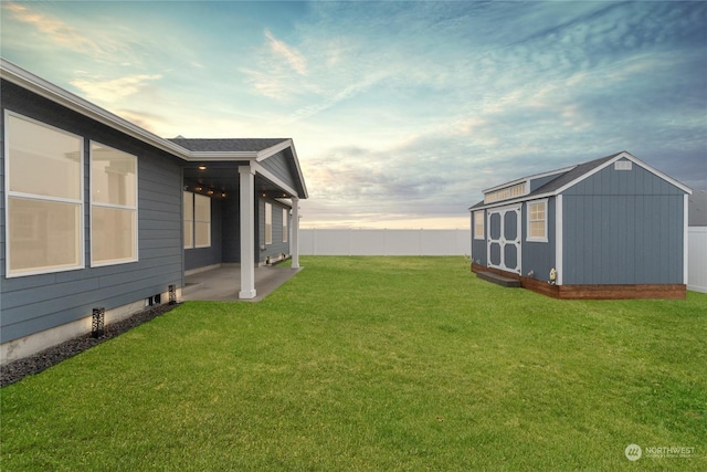 yard at dusk featuring a patio area and a storage unit