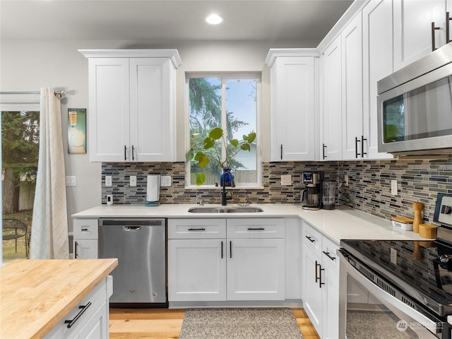 kitchen featuring tasteful backsplash, sink, white cabinets, and stainless steel appliances