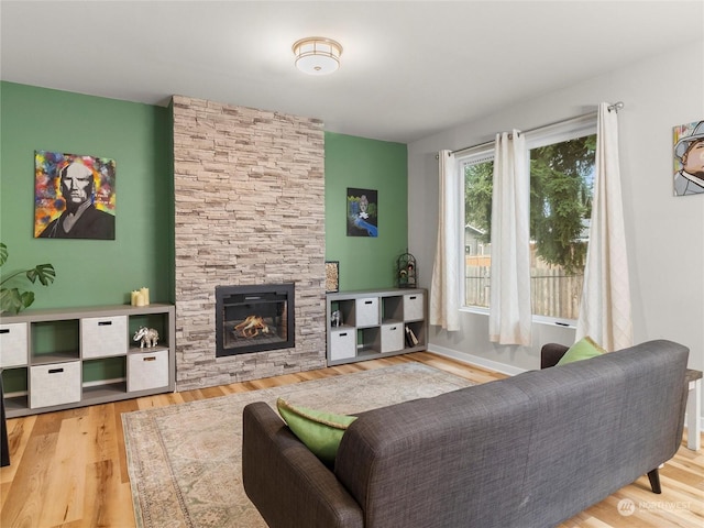 living room featuring a stone fireplace and light hardwood / wood-style floors