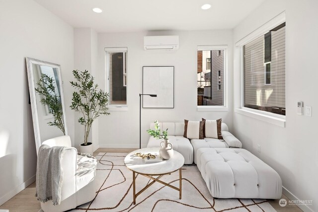 living area with light hardwood / wood-style floors, an AC wall unit, and plenty of natural light