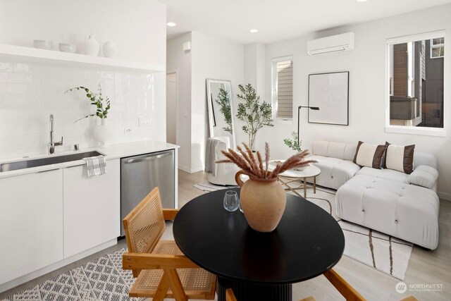 dining area featuring a wall mounted air conditioner, light wood-type flooring, and sink