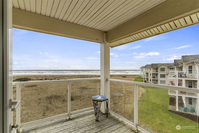 balcony featuring a view of the beach and a water view