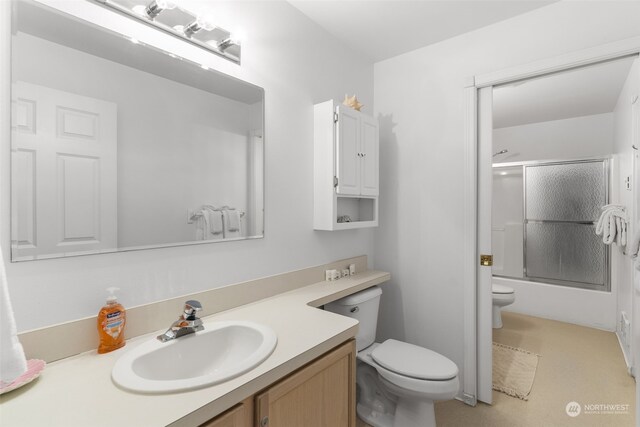 full bathroom featuring vanity, bath / shower combo with glass door, and toilet