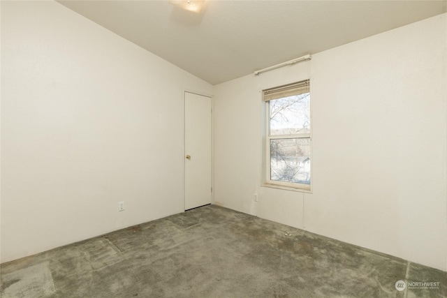 unfurnished room featuring carpet and vaulted ceiling