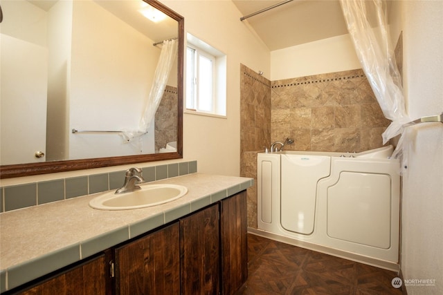 bathroom with vanity, parquet floors, and a tub