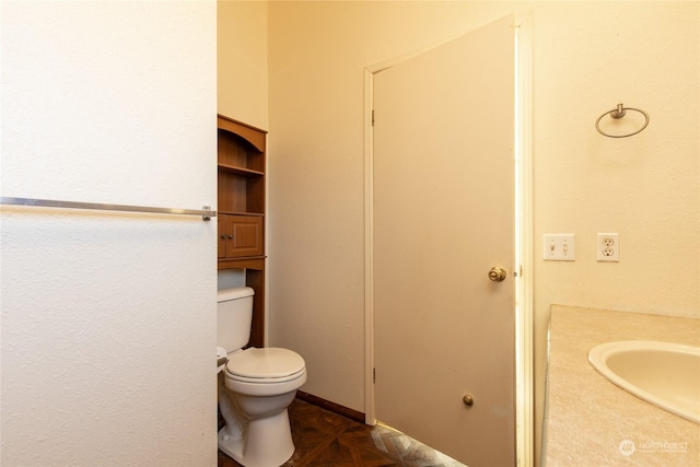 bathroom with vanity, toilet, and parquet flooring