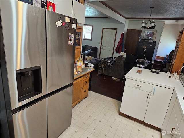 kitchen with pendant lighting, a textured ceiling, stainless steel refrigerator with ice dispenser, white cabinetry, and ornamental molding