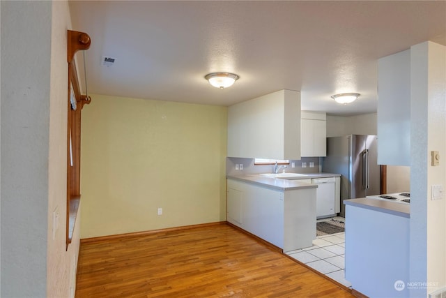 kitchen featuring a textured ceiling, dishwasher, white cabinetry, sink, and light wood-type flooring