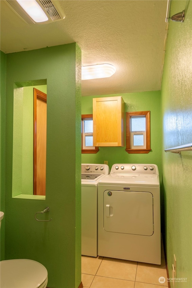 laundry area with washing machine and dryer, a textured ceiling, and light tile patterned flooring