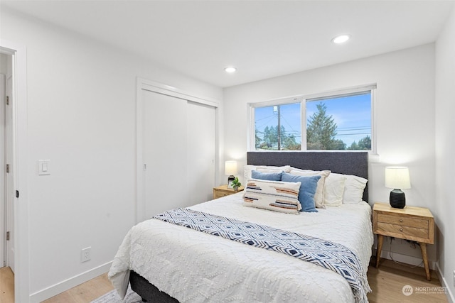 bedroom with light hardwood / wood-style floors and a closet