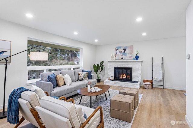 living room with light wood-type flooring and a brick fireplace