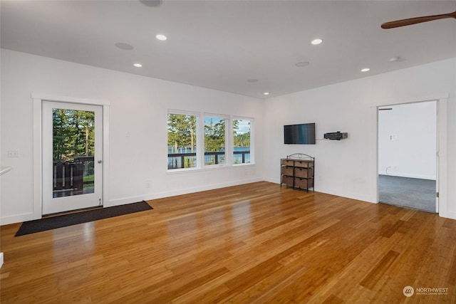 unfurnished living room featuring hardwood / wood-style flooring, a wealth of natural light, and ceiling fan