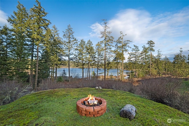 view of yard featuring a water view and an outdoor fire pit