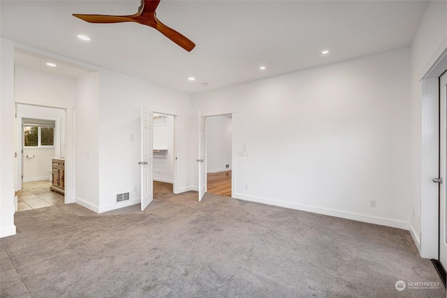 unfurnished bedroom featuring ensuite bath, ceiling fan, and light carpet