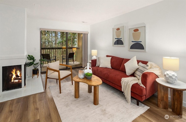 living room with a large fireplace, a textured ceiling, and light hardwood / wood-style flooring