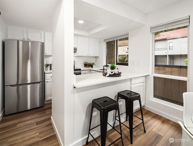 kitchen with a kitchen breakfast bar, sink, dark hardwood / wood-style floors, appliances with stainless steel finishes, and white cabinetry