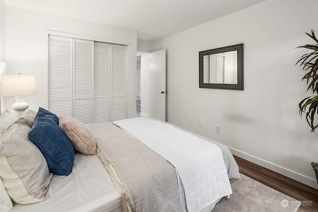 bedroom featuring a textured ceiling, dark hardwood / wood-style floors, and a closet