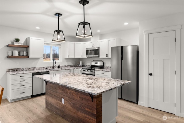 kitchen with light wood-style flooring, a kitchen island, light stone countertops, stainless steel appliances, and open shelves