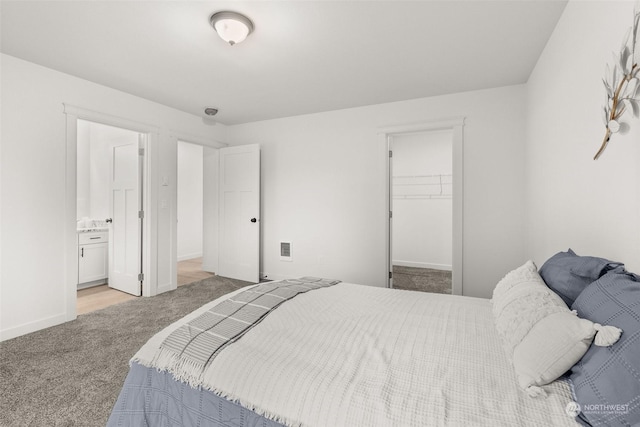 carpeted bedroom with a spacious closet, a closet, connected bathroom, and baseboards