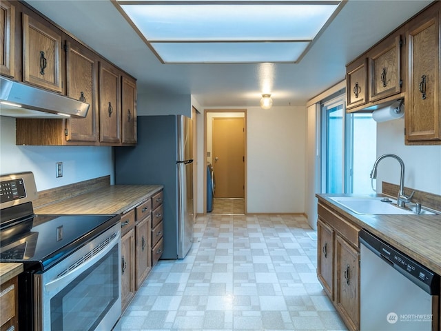 kitchen with stainless steel appliances, range hood, and sink