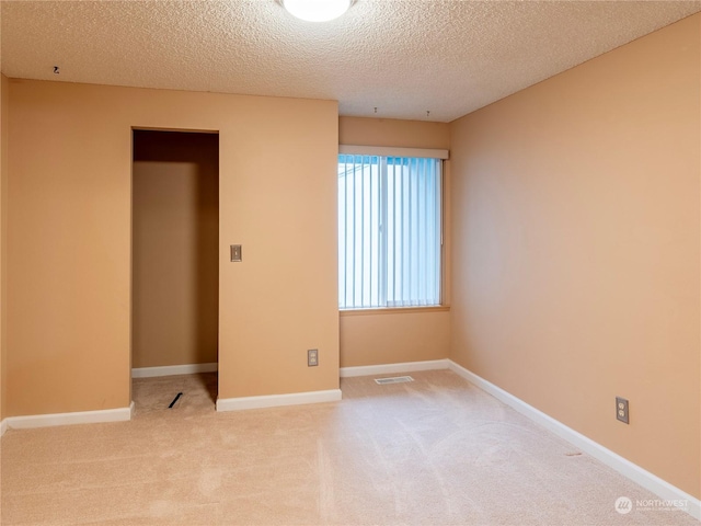 carpeted empty room featuring a textured ceiling