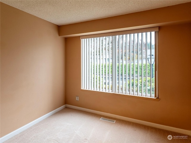 carpeted empty room featuring a textured ceiling