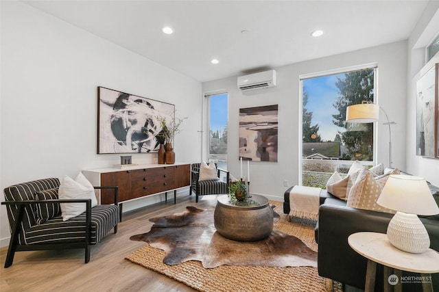 sitting room with an AC wall unit and light hardwood / wood-style floors