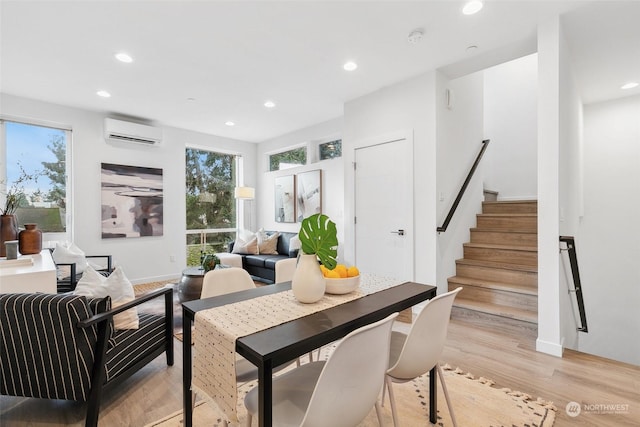 dining room with an AC wall unit, plenty of natural light, and light wood-type flooring