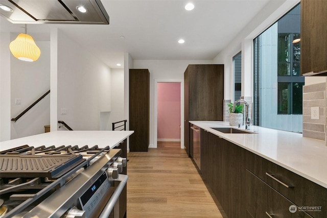 kitchen with sink, stainless steel appliances, pendant lighting, extractor fan, and light wood-type flooring