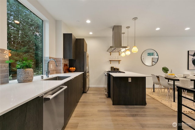 kitchen featuring sink, stainless steel appliances, pendant lighting, light hardwood / wood-style floors, and island range hood