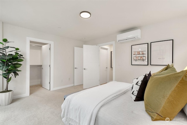 bedroom featuring a walk in closet, light carpet, a closet, and a wall mounted air conditioner