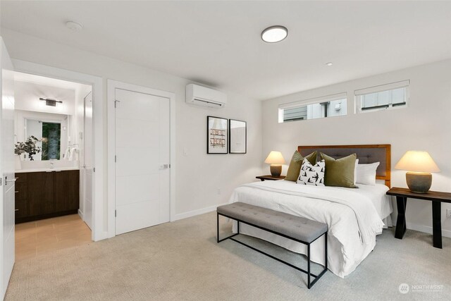 bedroom with ensuite bathroom, light carpet, and a wall unit AC