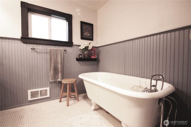 full bath featuring wainscoting, a freestanding tub, and visible vents