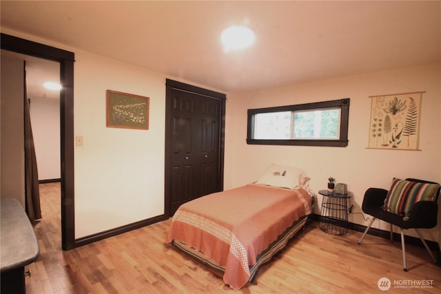 bedroom with a closet, light wood-style flooring, and baseboards