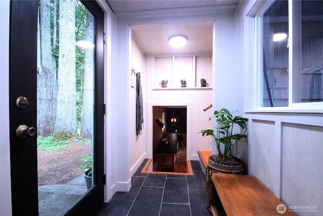 foyer entrance with dark tile patterned floors and a drop ceiling