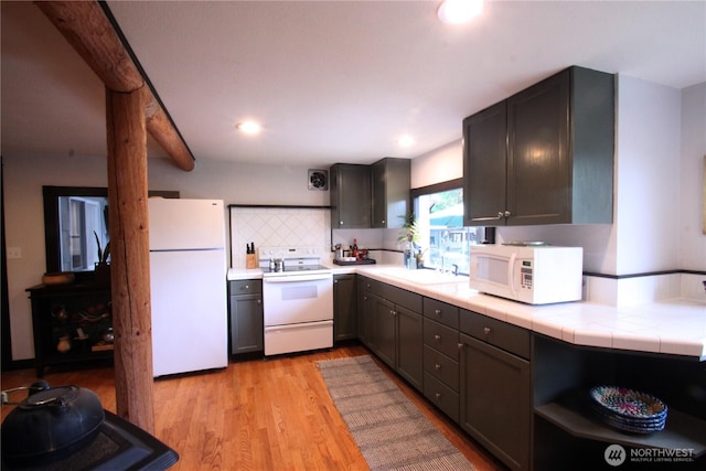 kitchen with tasteful backsplash, tile counters, a sink, light wood-type flooring, and white appliances