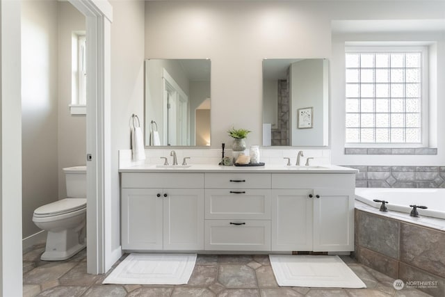 bathroom with vanity, toilet, and tiled tub